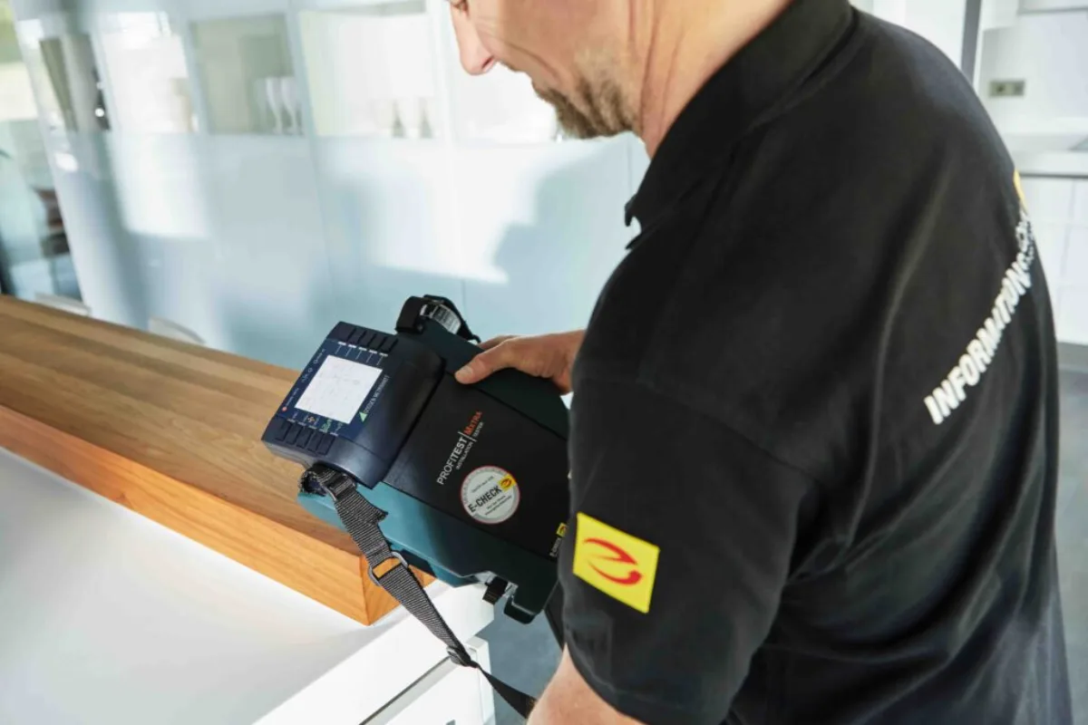 Elektromeister mit E-Check-Messgerät prüft eine private Hausverteilung